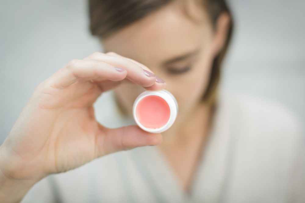 person holding round white and pink lipbalm