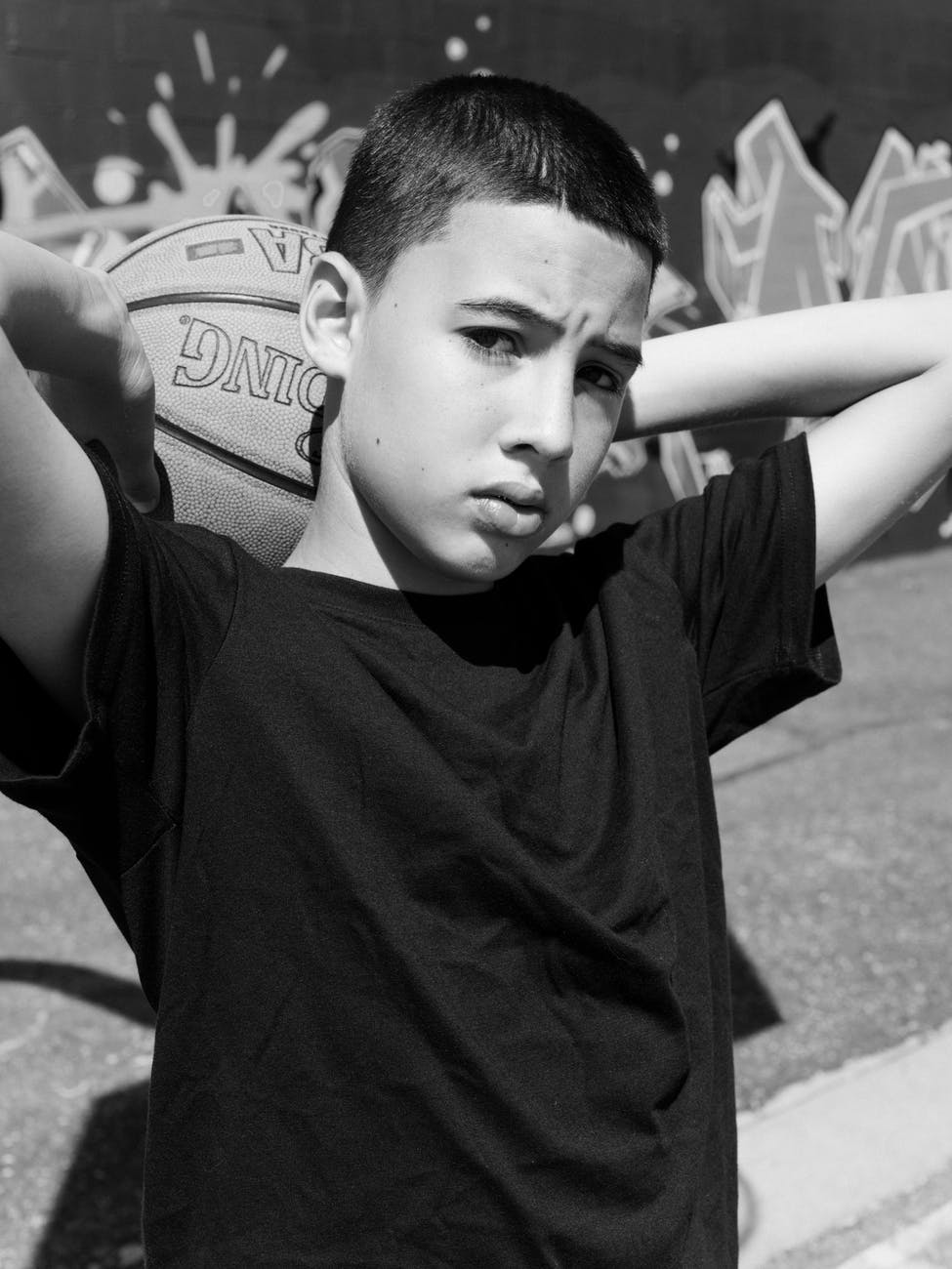 boy holds basketball at the back of his head