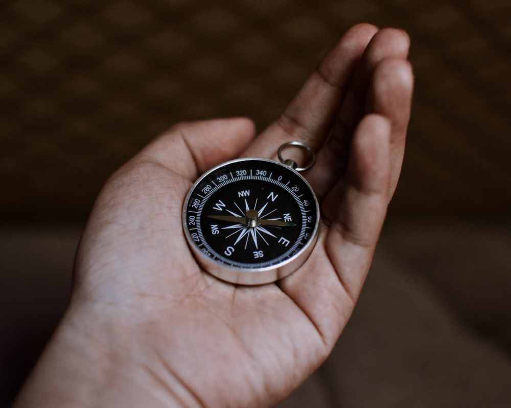 person holding a silver and black round compass